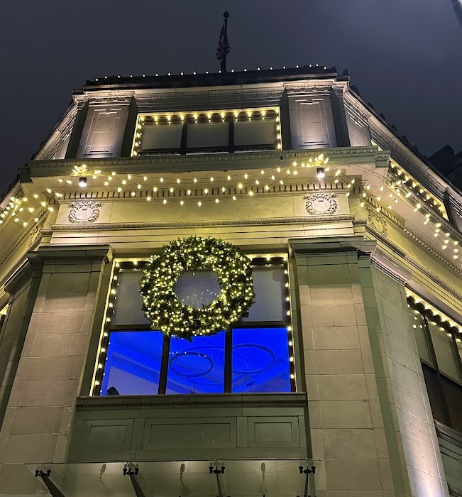 Upscale commercial storefront decorated with warm white Christmas lights and a lit wreath