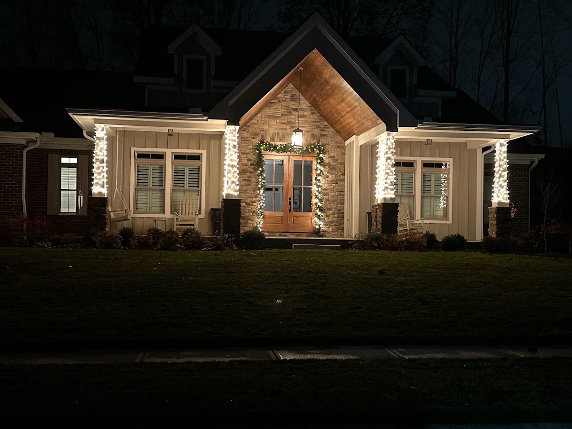 Front entryway with columns wrapped in warm white Christmas lights