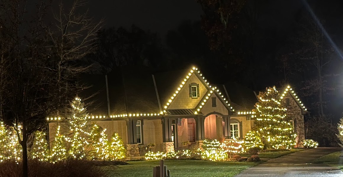 Grand home with full rooflines crisply outlined in warm white Christmas lights