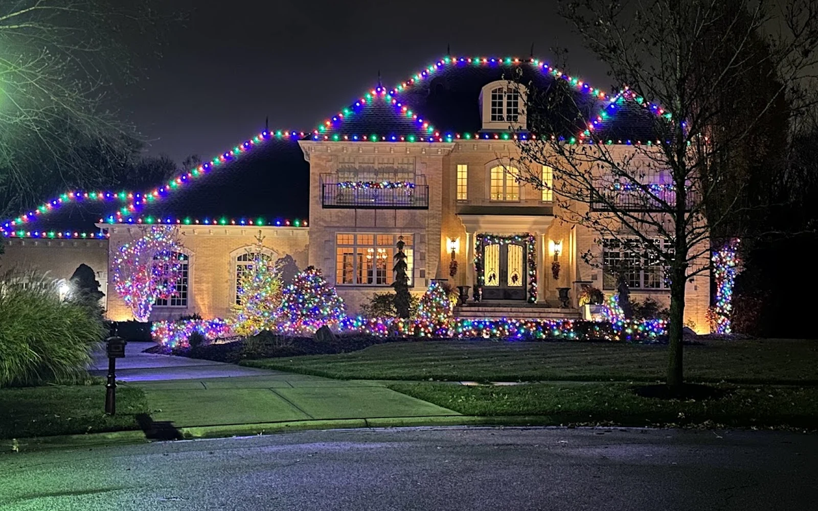 Multicolor Christmas lights outlining the roofline of a large home